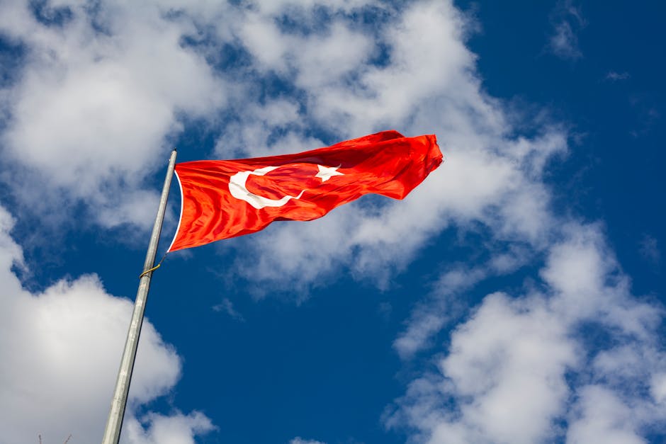 Low angle view of Turkish flag waving against a bright sky, symbolizing national pride and freedom.