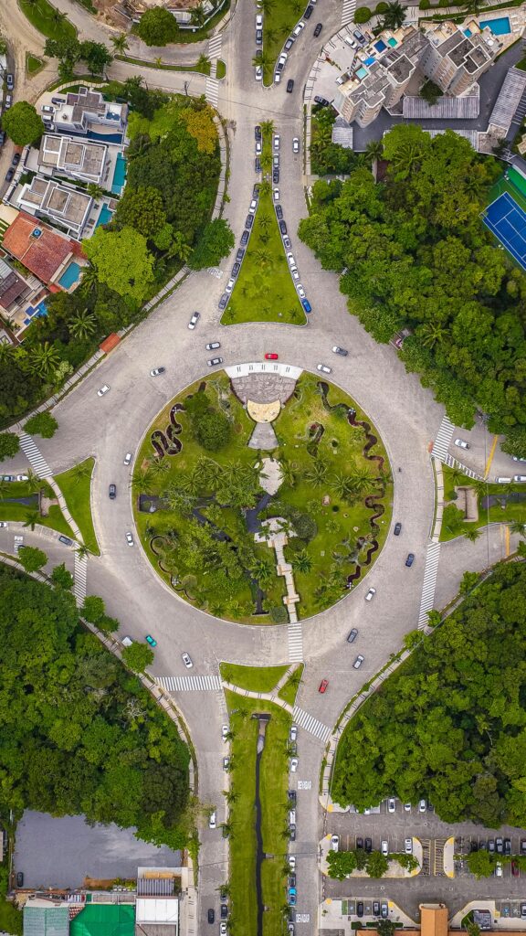 Aerial shot of a traffic roundabout surrounded by lush greenery in an urban area. Perfect for cityscape and travel themes.