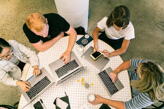 Top view of team collaborating in a modern office around laptops, discussing ideas.